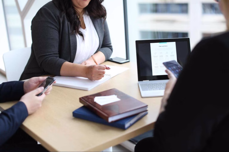 Business team discussing marketing strategies with laptops and notes, representing Fractional CMO services for cost-effective growth planning.