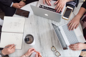 Marketing team collaborating on laptops and notes during a planning meeting focused on developing a website content strategy.